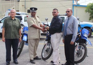  Mohamed Ally handing over the keys for the motor cycles to Balram Persaud while officials of Advance Security look on.