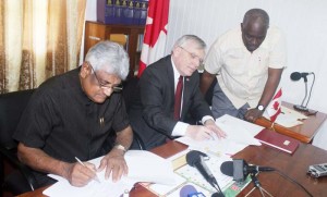 Signing the Agreement, from left: GECOM’s Chairman Dr. Steve Surujbally and High Commissioner Pierre Giroux