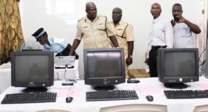 Assistant Commissioner Griffith (second from left ) and Commander Mansell and other officials examine the computers.