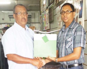 Hubern Evans (left) collects one of the two educational hampers from Yudesh Armogan, Company Manager. 