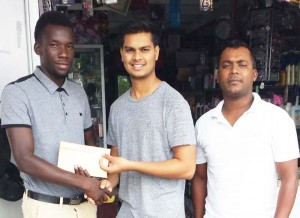 Linden Austin receives cheque from Satanand Mahabir in the presence of senior team captain Wahied Edwards. 
