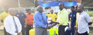  Finance Director of NaMilCo Fitzroy McLeod (2nd left) hands over the training equipment to Fruta Conquerors Secretary Daniel Thomas in the presence of Company officials and club members yesterday. 