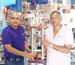 Proprietor of Trophy Stall Ramesh Sunich (right) presents one of the trophies to be competed for to Narchand Mohan. 