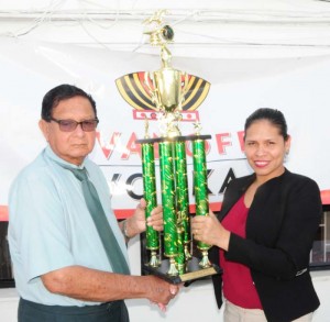  KMTC Chairman Cecil Kennard accepts the trophy from Maria Munroe.