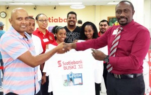 Rafeek Kassim (left), smiles as he receives one of the shirts from Scotiabank New Amsterdam Branch Manager Vibert Jones in the presence of other staff members and cricketers. 