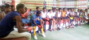The Under-16 boxers at the ‘Six Head’ Lewis gym Saturday pay rapt attention to Coach Sebert Blake during the early session. 