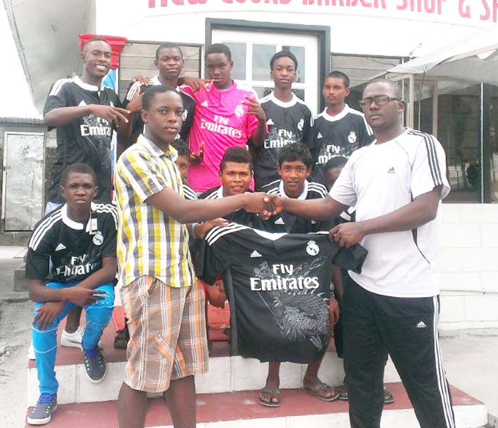 Vice President of Kuru Kururu Warriors FC Dale Roberts (right) receives one of the tops from Mr. Eldon Sobers in the presence of other club members.