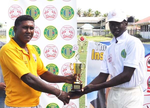 Man-of-the-Match Kevin Sinclair collects his trophy from Enterprise Busta Sports Club President Seemangal Yadram yesterday.