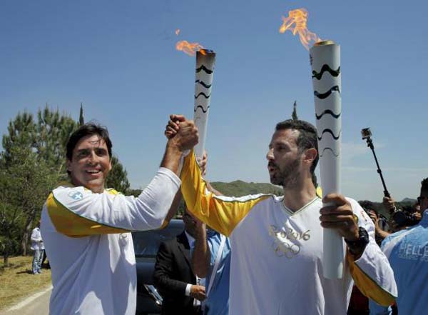 Olympic flame second torch bearer, former volleyball player Giovane Gavio from Brazil (L), passes the torch to third bearer Dimitrios Mougios as they attend the Olympic flame lighting ceremony for the Rio 2016 Olympic Games on the site of ancient Olympia, Greece, yesterday. Reuters/Yannis Behrakis