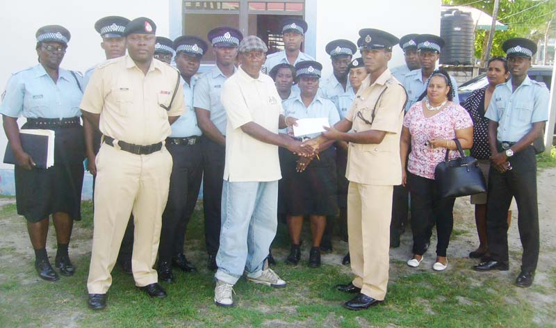  Assistant Superintendent Keith Williams presents the sponsorship cheque to Coordinator and Club Coach Randolph Roberts, while other police officers and club officials enjoy the moment.
