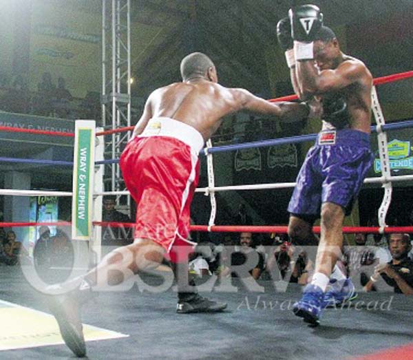 Revlon Lake (left) connects with a stiff right to the body of Anthony Woods during their five-round Contender boxing match. (Jamaica Observer)