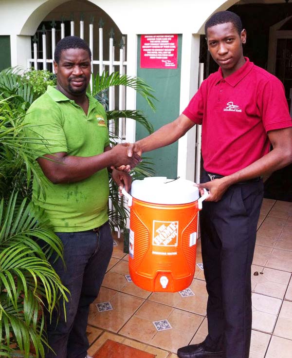  Sleepin International Hotels Rep. Shaquel Crackwell (right) hands over the Water Cooler to Buxton Stars Coach, Sherman David.