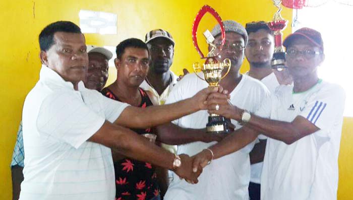 Captain of the Underdog team James Ramnarine (left) accepts the trophy from Mohamed Sheriffudeen in the presence of his team mates. 