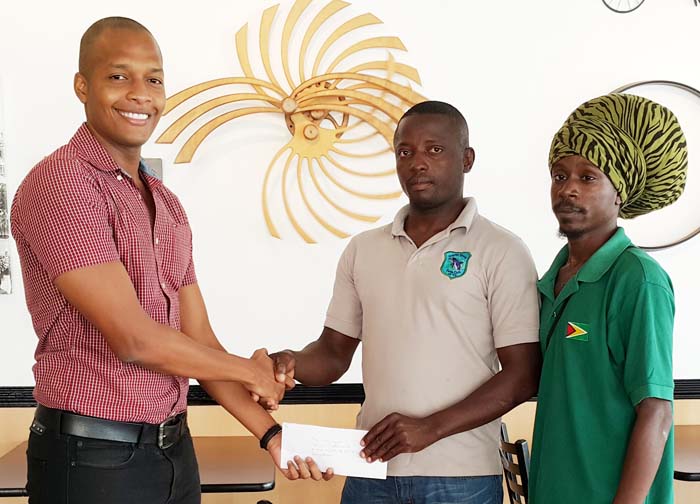  CEO of German’s Restaurant Mr. Clinton Urling (left) hands over the cheque to President of the Dolphin Speed Swim Club Mr. Paul Mahaica while a representative of the Club looks on. 