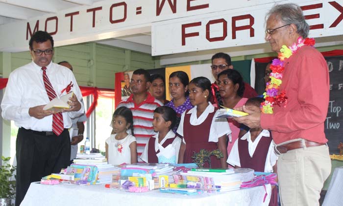 Dr Surendra Persaud (extreme left) and Dr Rupert Roopnaraine (extreme right) flank the pupils and others during Monday launch of the Scholarship Foundation.