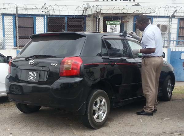 A detective dusts the recovered car for fingerprints. 