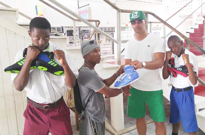 Linden Alphonso (second, right) hands over some of the gear to Coach, Orlan Rogers while two of the boxers strike a pose.