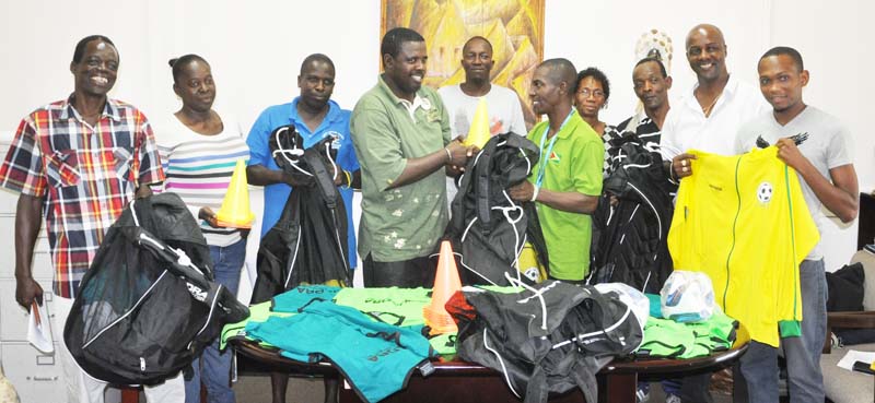 EDFA Secretary Gidel Austin hands over one of the bags with equipment to BV Triumph United Coach Kester Garnett in eth presence of EDFA President Alfred King (2nd right) and other coaches.