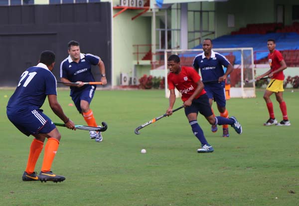 National U-21 player Kareem McKenzie (red jersey) runs at the GCC defence during a practice game recently.