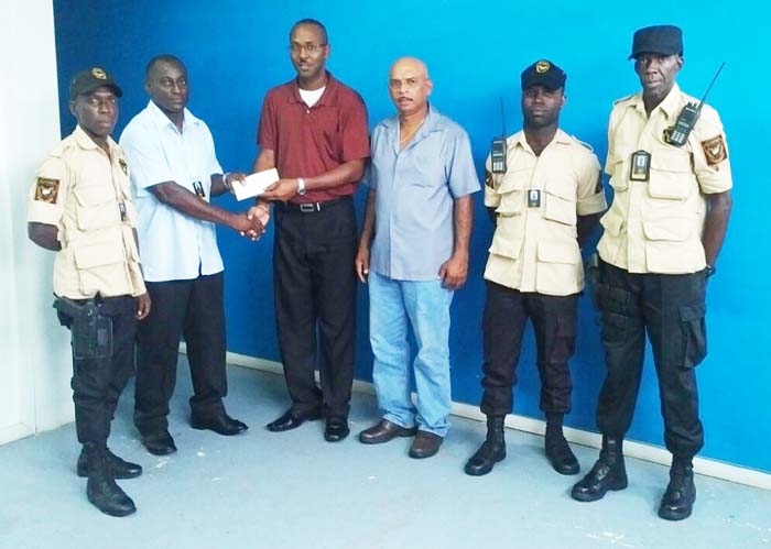 Quality Control Officer of Queensway Security Service, Mr. Ron Marks (2nd left) hands over sponsorship cheque to GuyanaNRA Secretary Ryan Sampson in the presence of Mr. Mahendra Persaud (3rd right) and ranks of Queensway Security Service.