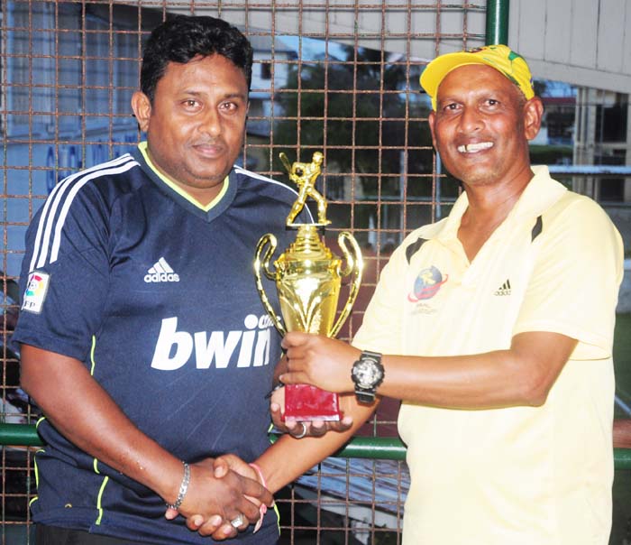 Mahase Chunilall (right) accepts the trophy from Surendra Hiralal of GYO as Superior Woods- Superiors Woods captain Rudolph Rodrigues (left) collects the runner up prize from Divesh Ramjattan of GYO. 