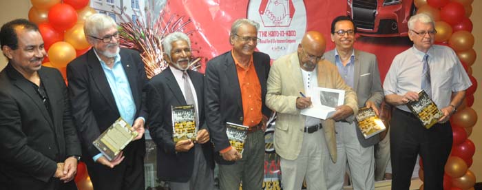 Seecharan signs one of his books as others including Minister Roopnarine (4th from right) and Murray (3rd from left) share the moment.