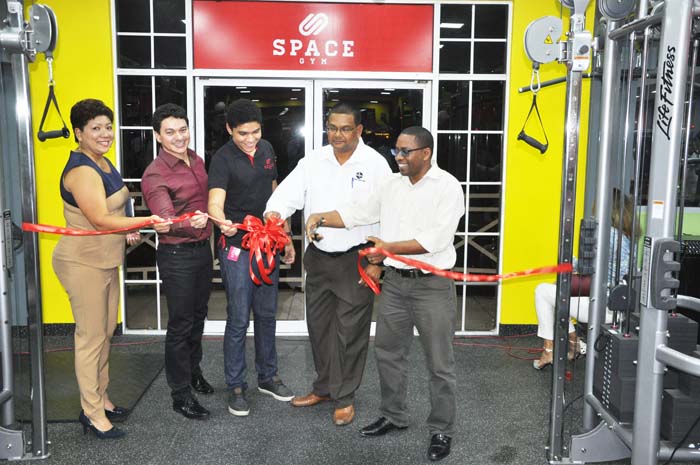 NSC’s Seon Erskine cuts the ribbon to officially open the Space Gym in the presence of from left, Ms Kathy Johnson, Mr Sergio Matos, Mr Lucas Matos and Mr Indranauth Haralsingh.
