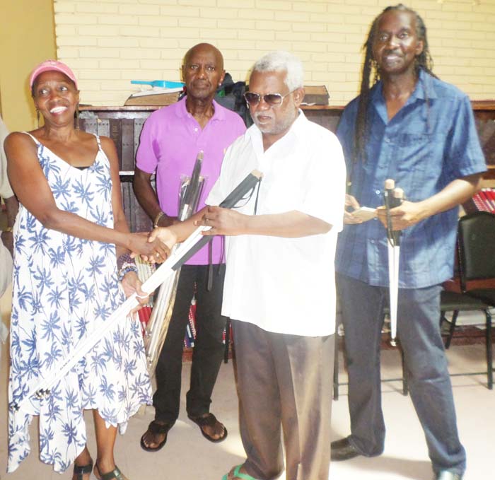 Three of the Wilburg siblings, from left, Desiree, Aubrey and Lyndon) hand over the canes to Mr Cecil Morris.