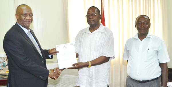 Minister of State, Joseph Harmon receives the report into the inquiry of Guyana Oil Company Limited from Chairman of the Board of Inquiry, Winston Cosbert, in the presence of Julius Wright (at right).