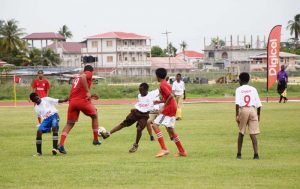 CSAS striker Elijah Johnson (red uniform) attempts to go through a host of Supply players during their encounter yesterday.