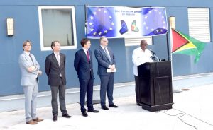 Finance Minister Winston Jordan delivers remarks in the presence of European Union (EU) Ambassador to Guyana, Mr. Jernej Videtič (second from right) along with other EU representatives, during the ceremony at the Marriott Hotel.