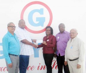 GUYOIL Marketing Secretary Demaley Clarke hands over sponsorship cheque to RHTY&SC Secretary/CEO Hilbert Foster in the presence of other Company Officials.