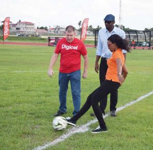 Head of Marketing Jacqueline James expertly executes the ceremonial kick off in the presence of CEO Kevin Kelly (left) and Director of Sport Christopher Jones.