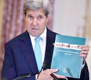 US Secretary of State holding a copy of the 2016 TIP Report