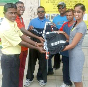 Latchman Yadram of Enterprise CC receives the donation from Sales Clerk Lisa Seegobin in the presence of his team mates.