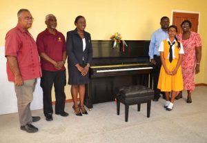 Minister Nicolette Henry (third from left) and members of the Guyana Music School with one of the newly acquired pianos.