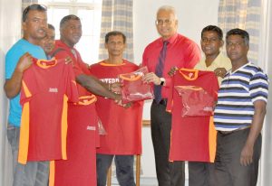 Operations Manager of Assuria Insurance Clyde Muntslag (3rd left) presents one of the jerseys to Enterprise Legends captain Seemangal Yadram in the presence of his team mates.