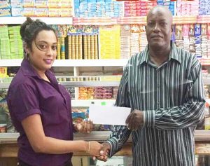  A Representative of the Hyper Malt Drink presents the cheque to Representative Compton Sancho of the Guyana Cup Organising committee. 