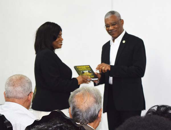 President David Granger receives a copy of the book from co-author Khalilah Campbell.