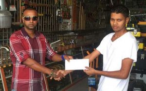  A representative of the Muneshwar General Store presents the cheque to Representative Rovin De Souza (left) of the Guyana Cup Organising committee.