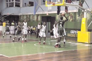 Guyanese centre, Berbician, Jermaine King (right) goes up for a put-back in the paint Monday night against Suriname at the Cliff Anderson Sports Hall. 