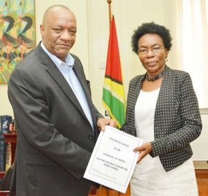 Commissioner, Retired Colonel Windee Algernon hands over the Preliminary Report of the Commission of Inquiry to Minister of State, Joseph Harmon.