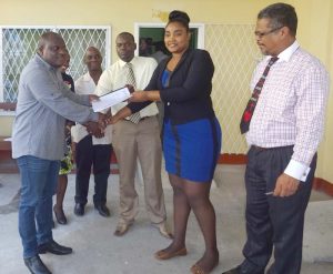 At right, Chief Labour, Occupational Safety and Health Officer Charles Ogle looks on as Town Clerk Royston King (left) receives the report