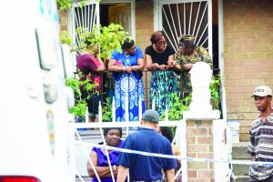 Neighbors and family gather outside as police investigate the double fatal shooting. (New York Daily News photo)