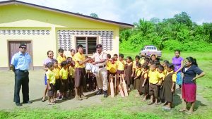 Commander of “F” Division Ravindradat Budhram hands over the gear to students and teachers of Kurupukari Primary School