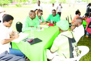 Minister of State, Joseph Harmon and Minister within the  Ministry of Natural Resources, Simona Broomes interacting  with residents of the public at the outreach in Linden