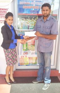 Amrita Bahadur a representative of Regal Stationary and Office Centre presenting the sponsorship to Mahendra Samaroo for the staging of the North Pakarimas Summer Fiesta.