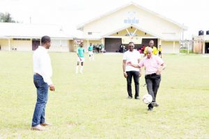  NAMILCO’s Affeez Khan kicks the ball off after receiving a pass from GFF President Wayne Forde (left) to signal the start of competition.  