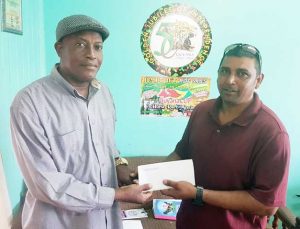Proprietor of A. Khan Lumber yard presents  the cheque to Campton Sancho (left).
