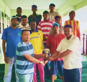 President of the Everest CC Rajesh Singh (left) presents the trophy to Mahaica Captain Avinash Persaud in the presence of his team mates.